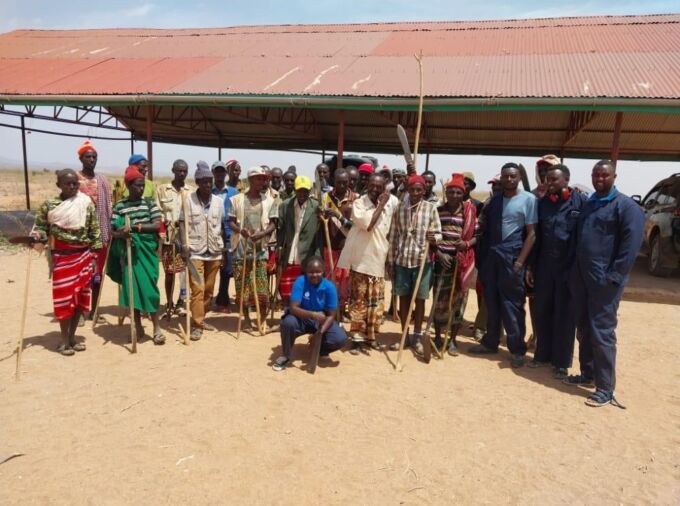A group of pastoralists and Morans from Kor in Marsabit, Kenya, who are being employed to remove weeds and improve the land through the application of biochar. Standing with PlantVillage Dream Team members, from right, are Rashid Buroya (in blue overalls), Fofen Lawrence and John Mayieka, with Dream Team lead Melodine Jeptoo in the front. Credit: PlantVillage. All Rights Reserved.