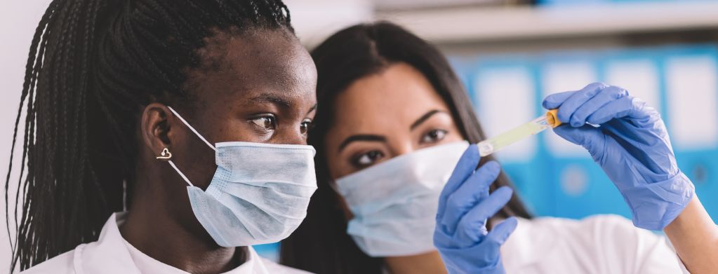 Two scientists wearing masks looking at a test tube