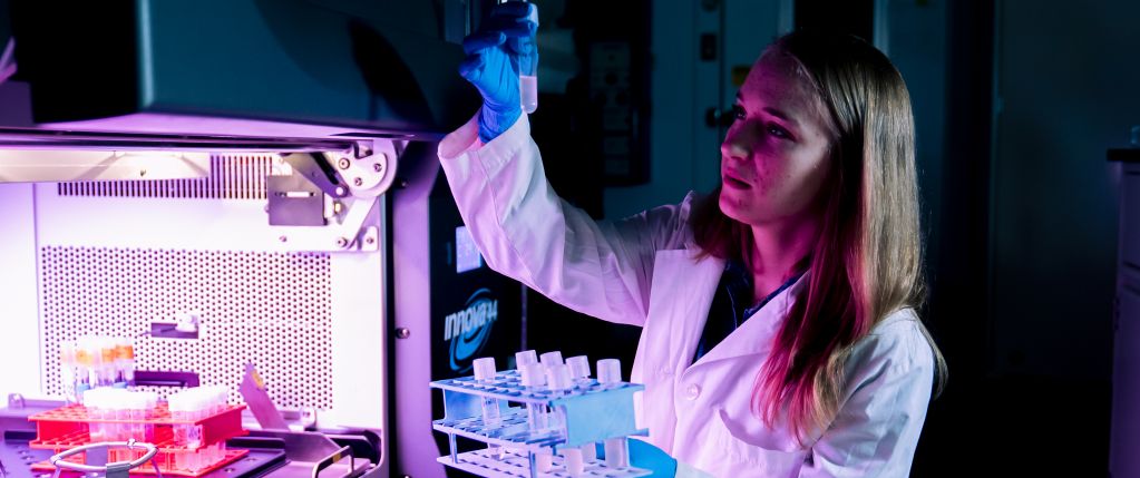 Banner image for new research proposal page. Scientist holding up a test tube and examining it.