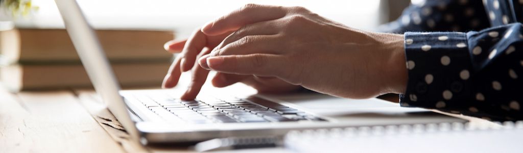 Hands typing on a laptop keyboard