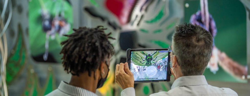 Media and Collaborative Banner: Two people looking at a tablet in front of an interactive sculpture