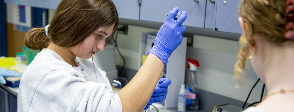 Banner for Scientists in Residence Page: a high school student using a pipette