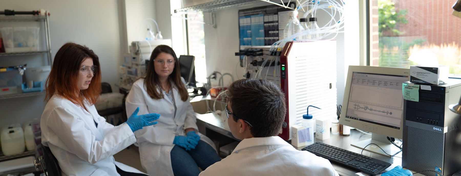 3 biotechnology graduate students collaborate in the lab
