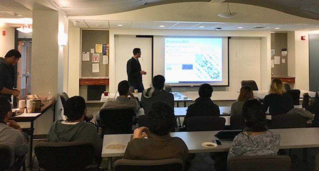 Zach Fuller, in front of a project slide, talks in front of a room of students.