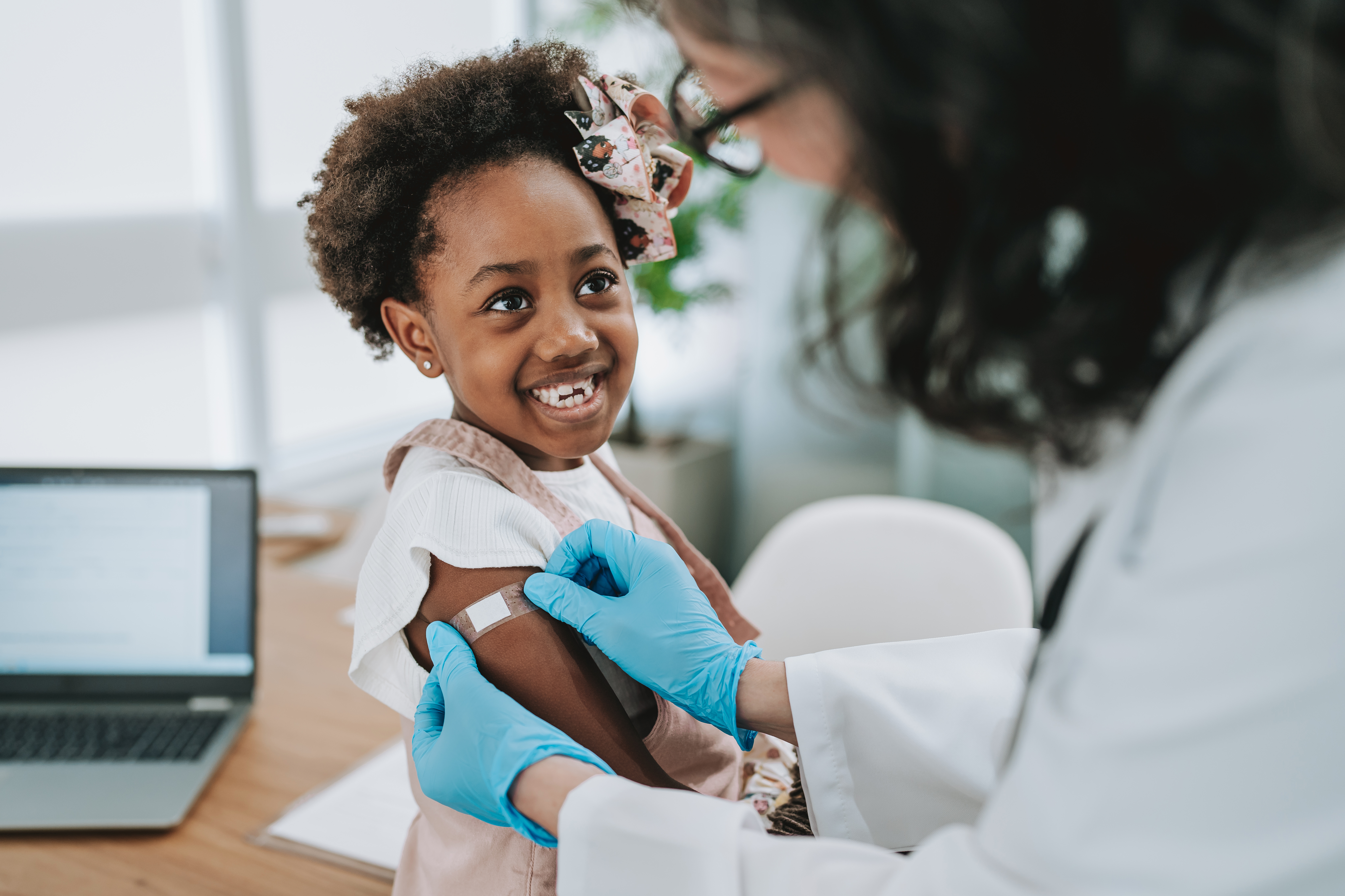 A young girl smiles as she receives a vaccine