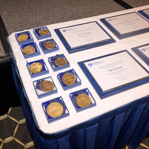 Awards and medals on a table at the 2023-24 Graduate Student Awards, hosted by the Graduate School at Penn State.