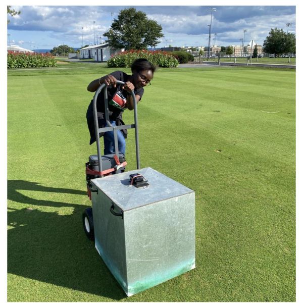 Study first author Maureen Kahiu, who earned her master’s degree from Penn State with this research project, maneuvers a light box on a research fairway, used to take closeup photos of turfgrass damage resulting from fungicides that golf course managers use to suppress diseases such as dollar spot. Credit: Penn State. Creative Commons